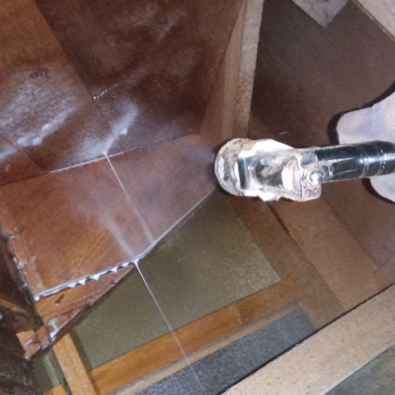 床下木材にシロアリ駆除剤を吹き付けている様子