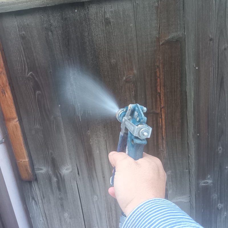 木塀にシロアリ駆除剤を吹き付ける様子