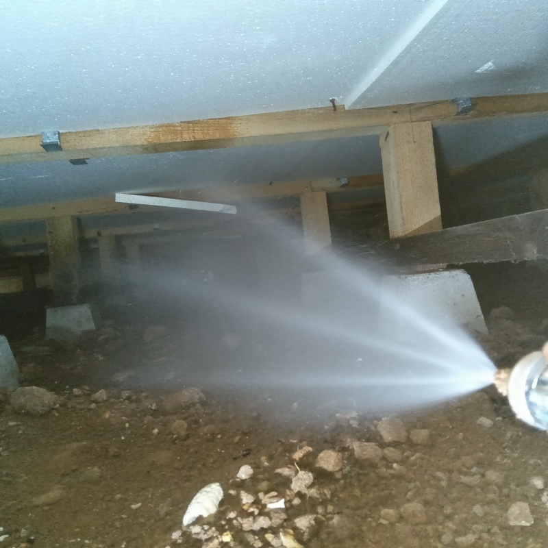 地面にシロアリ駆除剤を吹き付けている様子