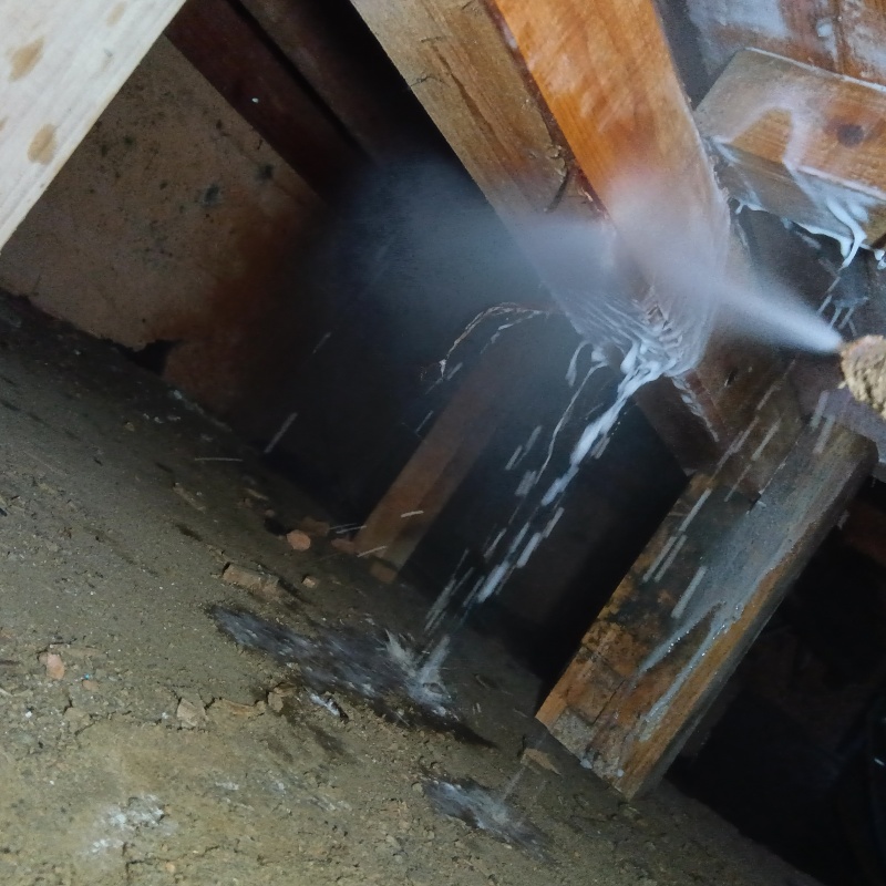 床下木材にシロアリ駆除剤を吹き付ける様子