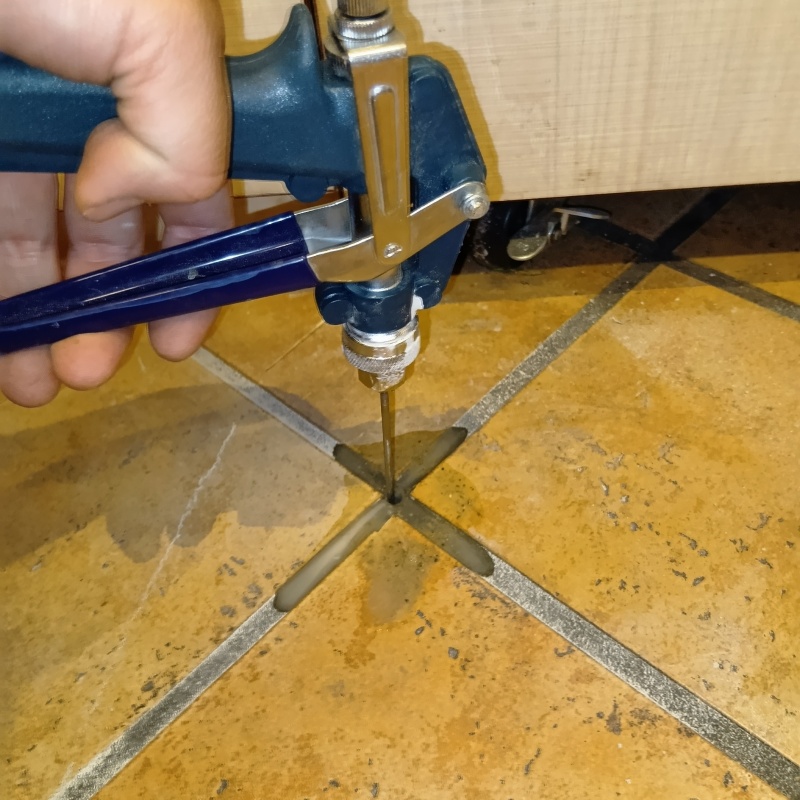 床の目地に穴を開けてシロアリ駆除剤を注入している様子