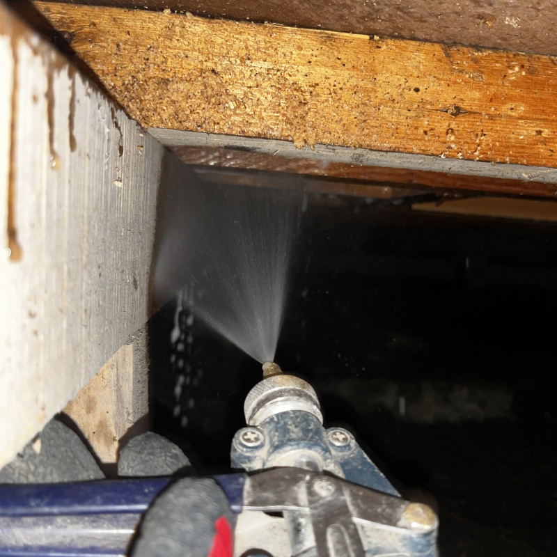 床下木材にシロアリ駆除剤を吹き付ける様子