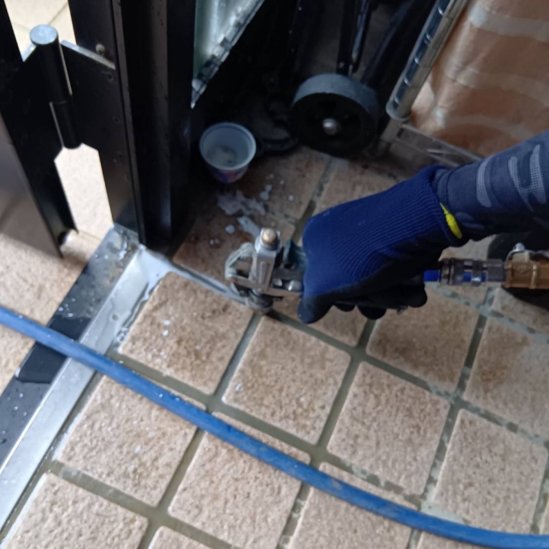 玄関の床にシロアリ駆除剤を注入する様子