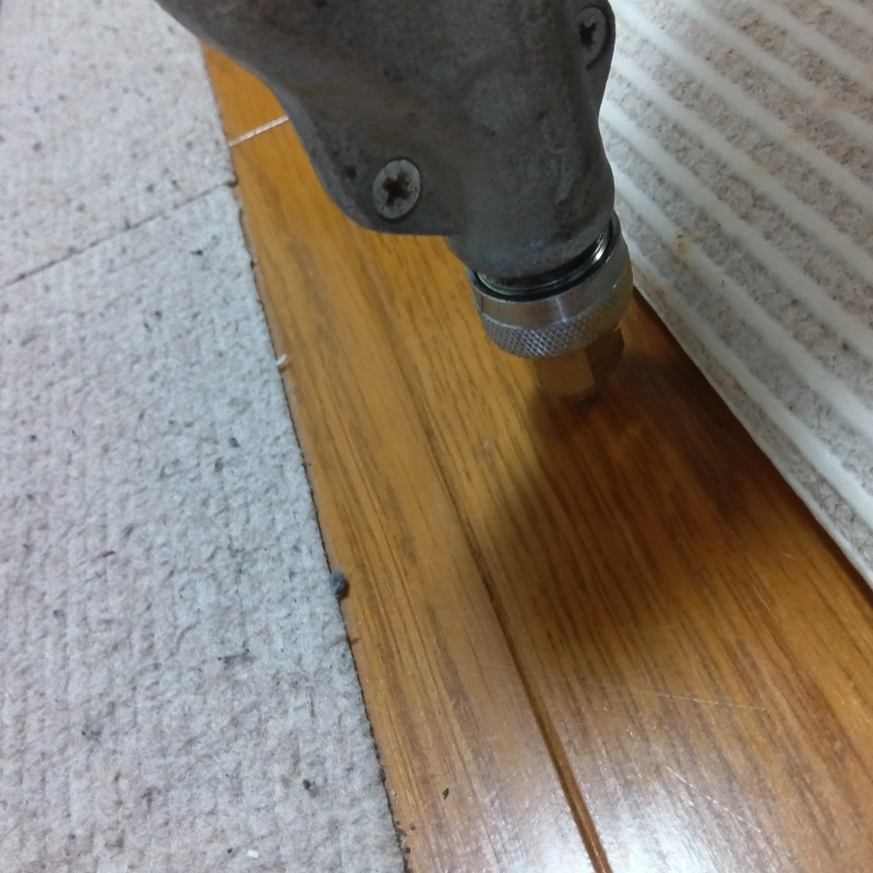 居間の床にシロアリ駆除剤を注入する様子