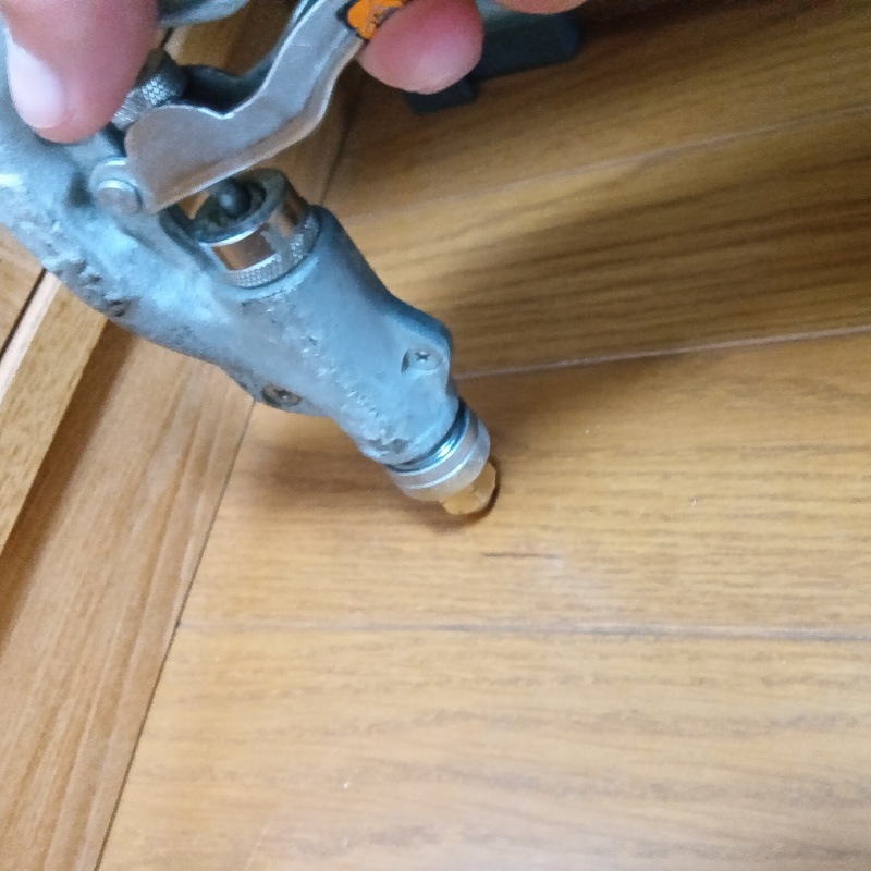 居間の床にシロアリ駆除剤を注入する様子