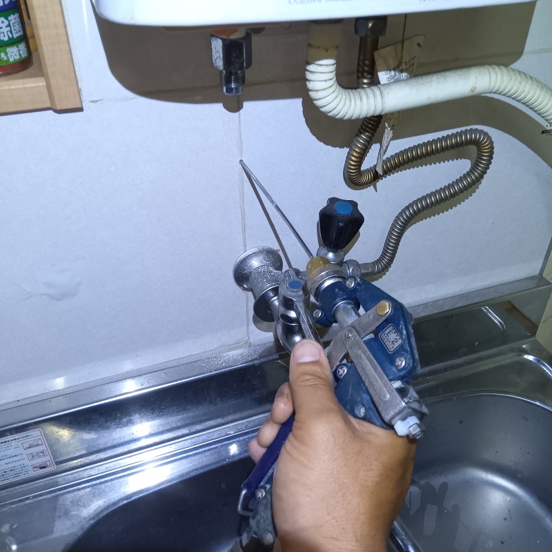 キッチンの壁にシロアリ駆除剤を注入する様子