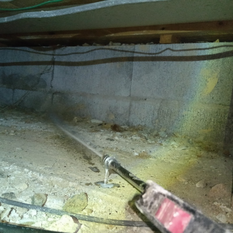 床下の土壌にシロアリ駆除剤を散布する様子