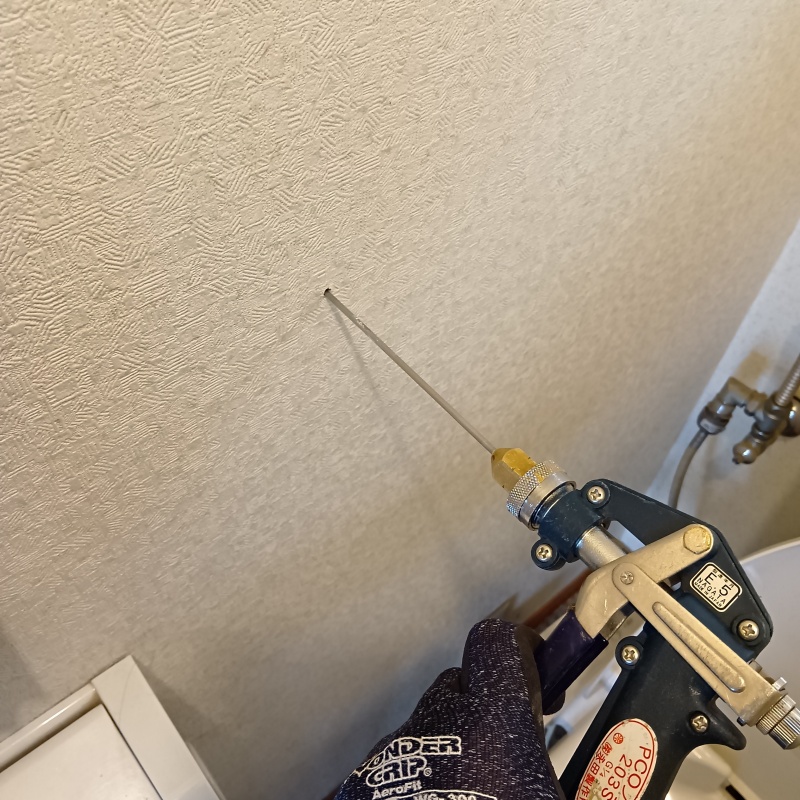 トイレの壁にシロアリ駆除剤を注入する様子