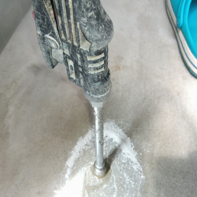 玄関の床にシロアリ駆除剤を注入する様子