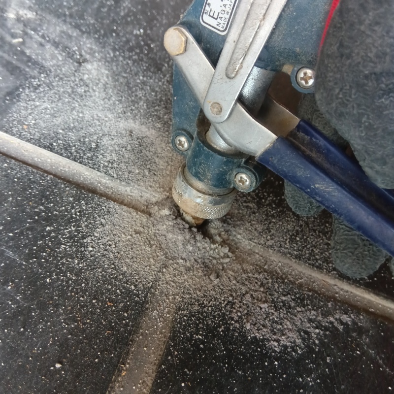 玄関の床にシロアリ駆除剤を注入する様子