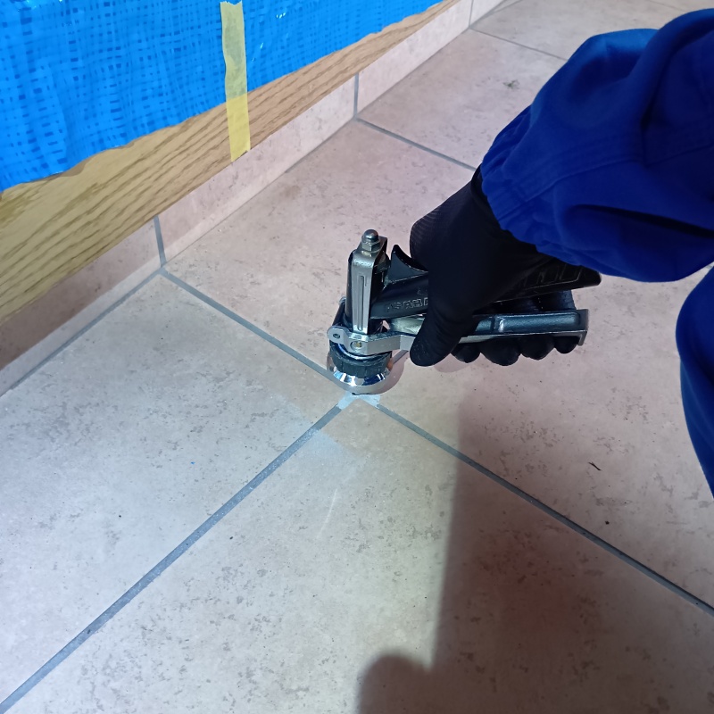 玄関の床にシロアリ駆除剤を注入する様子