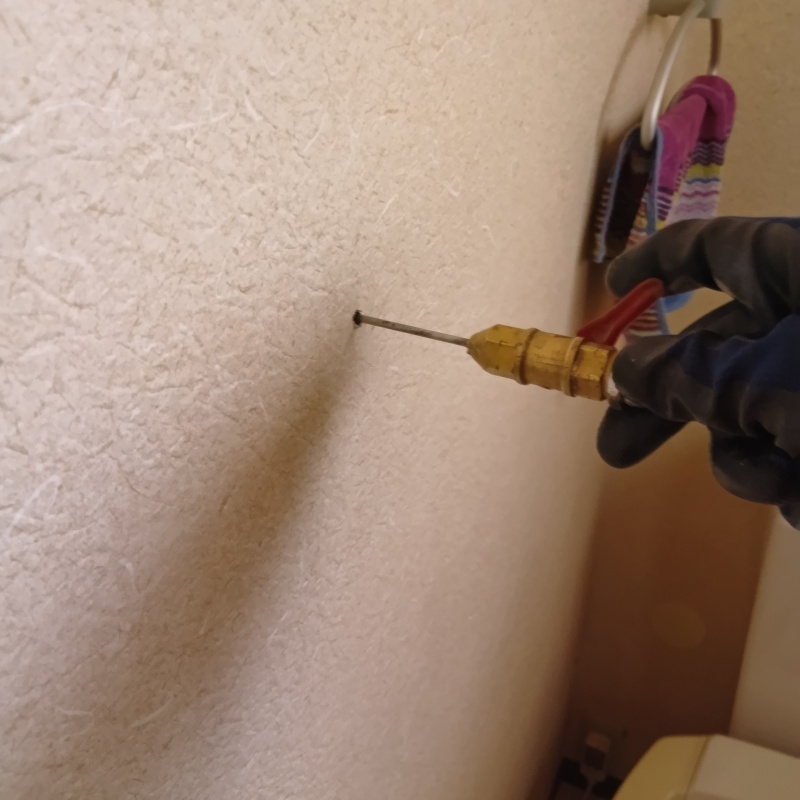 トイレの壁にシロアリ駆除剤を注入する様子