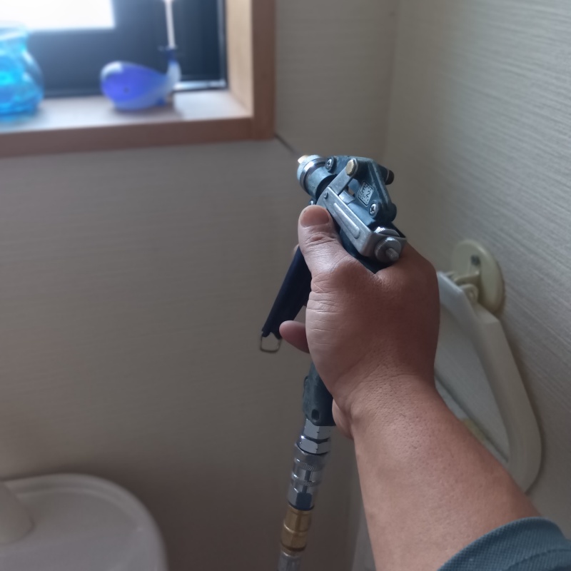 トイレの窓口にシロアリ駆除剤を注入する様子