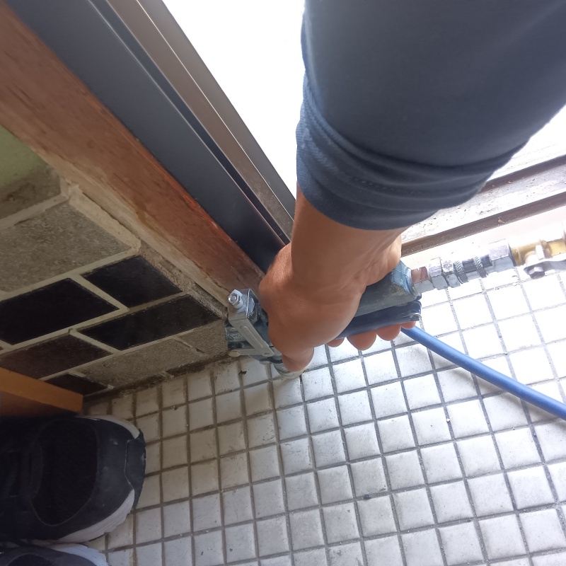 玄関の床にシロアリ駆除剤を注入する様子