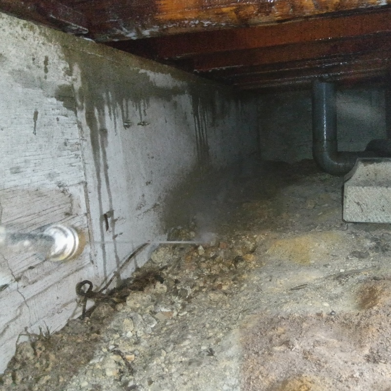 床下の土壌にシロアリ駆除剤を散布する様子