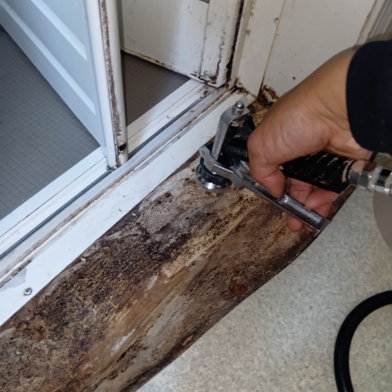 脱衣室の床にシロアリ駆除剤を注入する様子