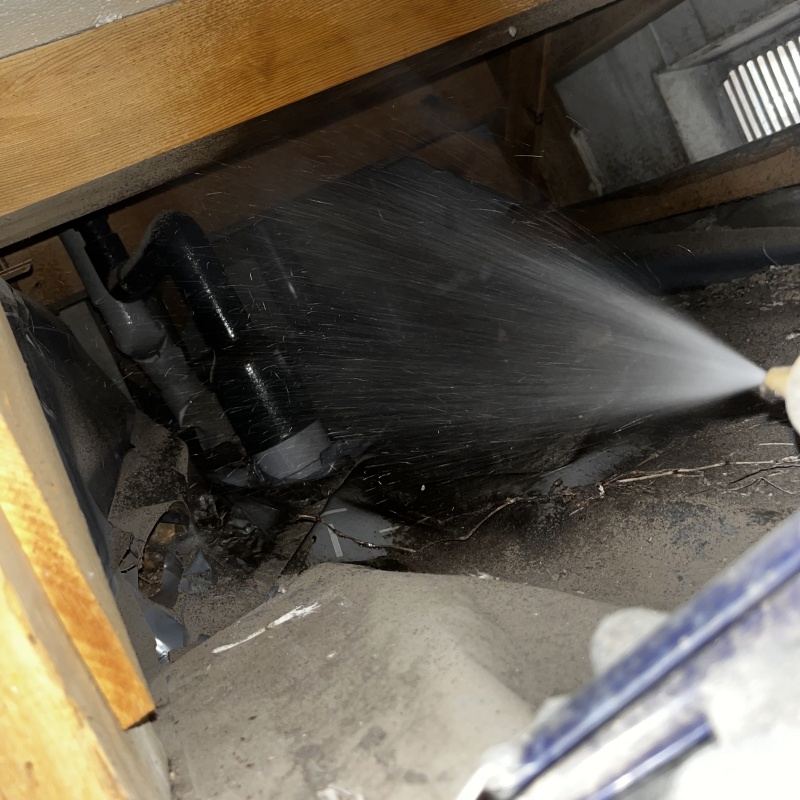 床下の土壌にシロアリ駆除剤を散布する様子