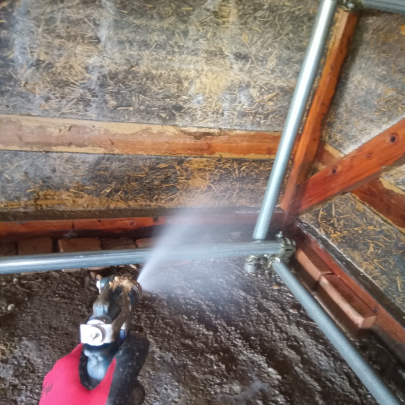 倉庫の土壌にシロアリ駆除剤を散布する様子