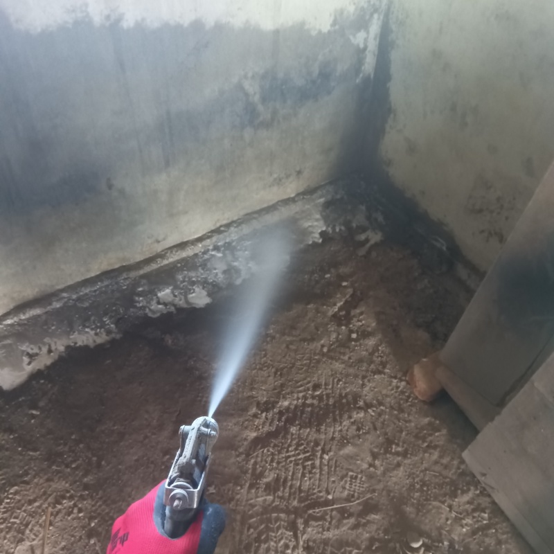 倉庫の土壌にシロアリ駆除剤を散布する様子