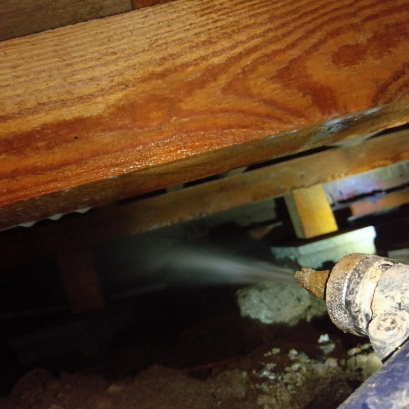 床下の土壌にシロアリ駆除剤を散布する様子