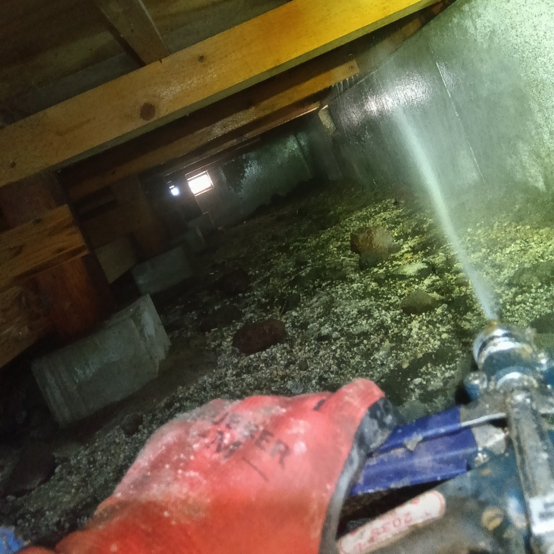 床下の基礎部分にシロアリ駆除剤を散布する様子