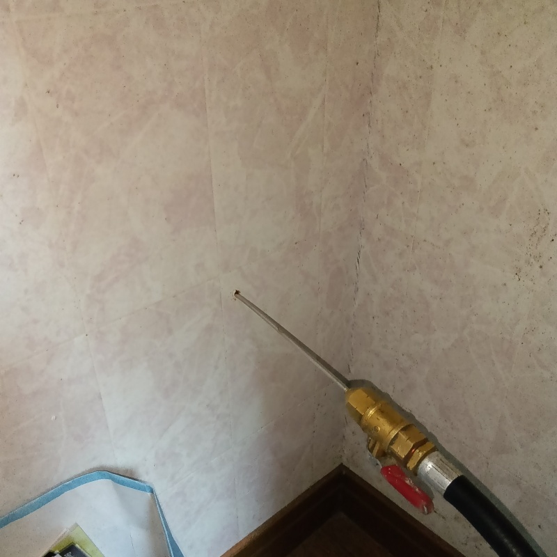 トイレの壁にシロアリ駆除剤を注入する様子