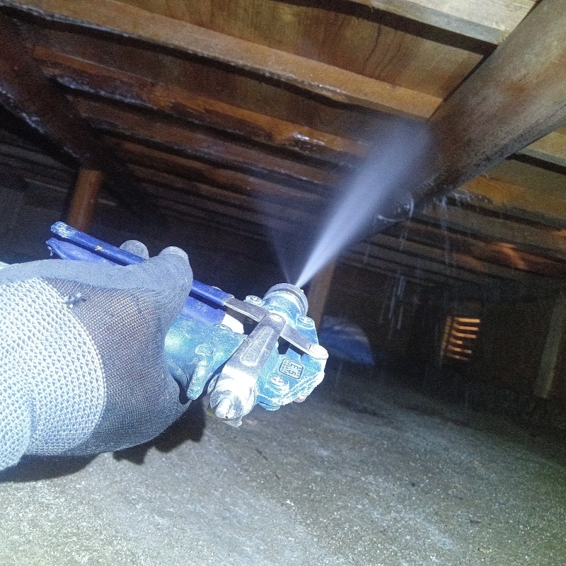 床下の木材にシロアリ駆除剤を散布する様子