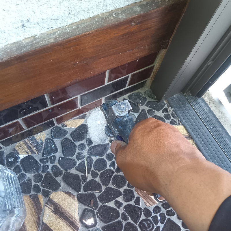 玄関の床にシロアリ駆除剤を注入する様子