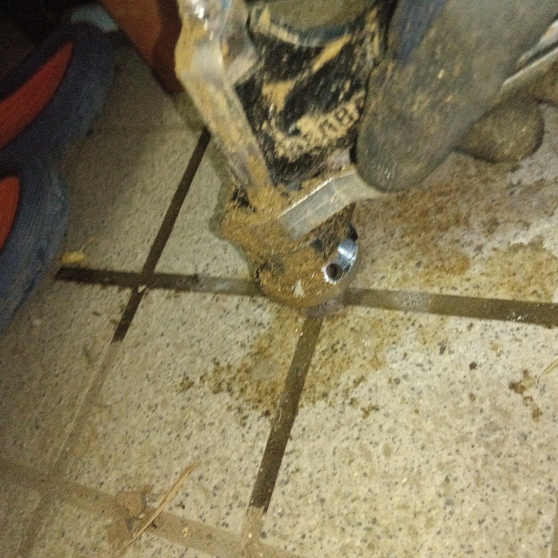 玄関の床にシロアリ駆除剤を注入する様子