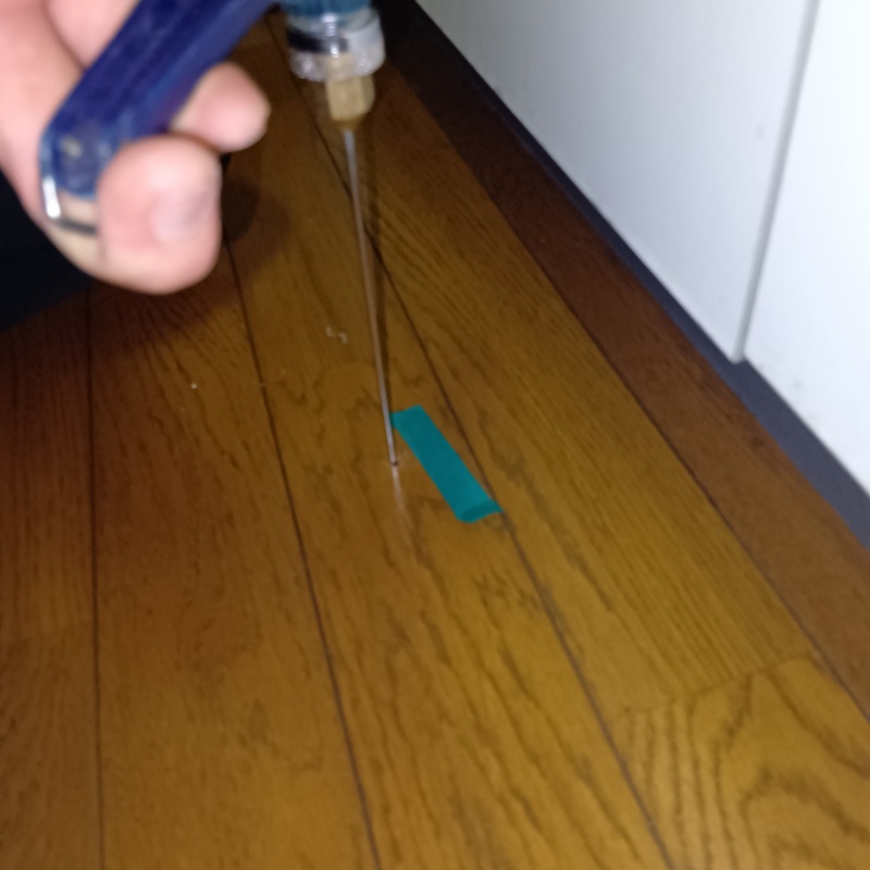 キッチンの床にシロアリ駆除剤を注入する様子