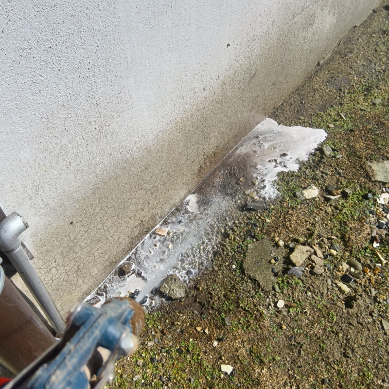 基礎まわりにシロアリ駆除剤を吹きつける様子