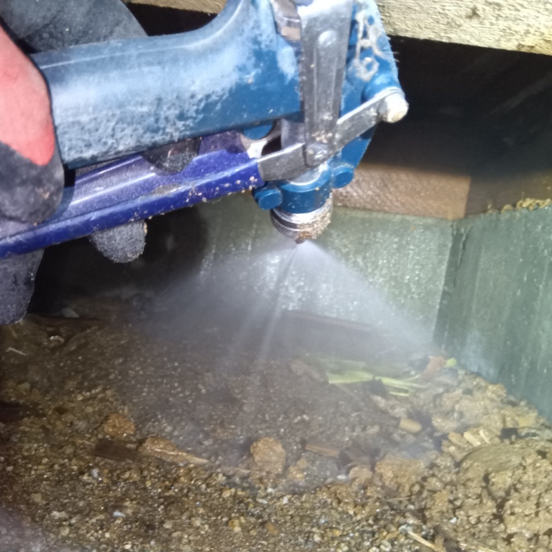 床下の土壌にシロアリ駆除剤を散布する様子