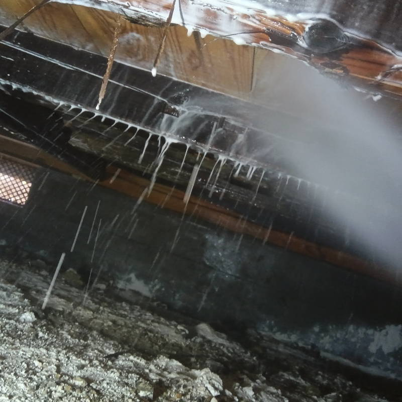 床下木材にシロアリ駆除剤を吹き付ける様子