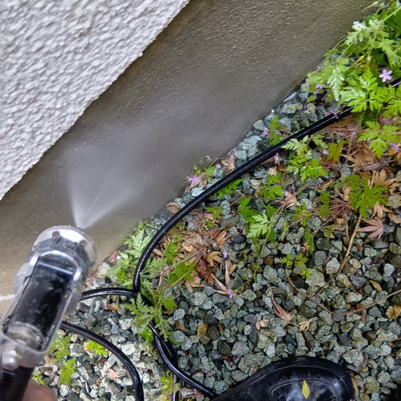 建物外周の土壌にシロアリ駆除剤を吹き付ける様子