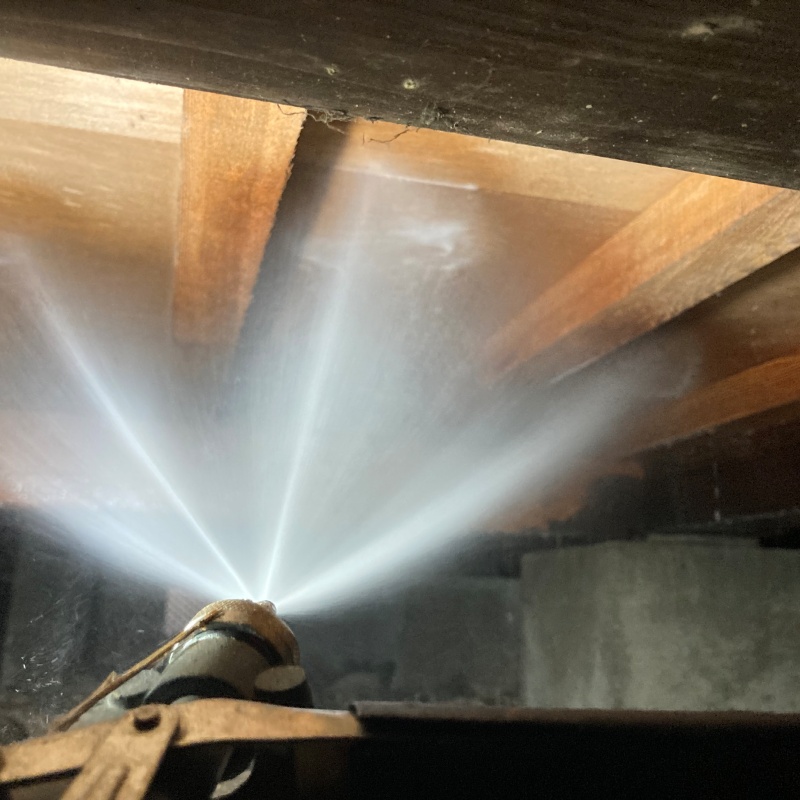 床下木材にシロアリ駆除剤を吹き付ける様子