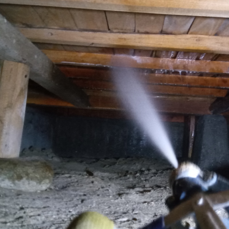 床下木材にシロアリ駆除剤を吹き付ける様子