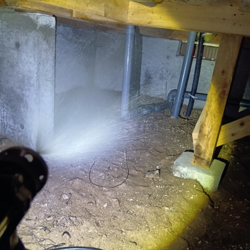 床下の土壌にシロアリ駆除剤を散布する様子