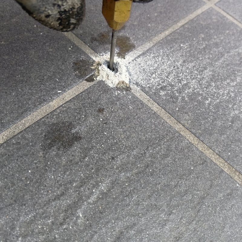 玄関の床にシロアリ駆除剤を注入する様子