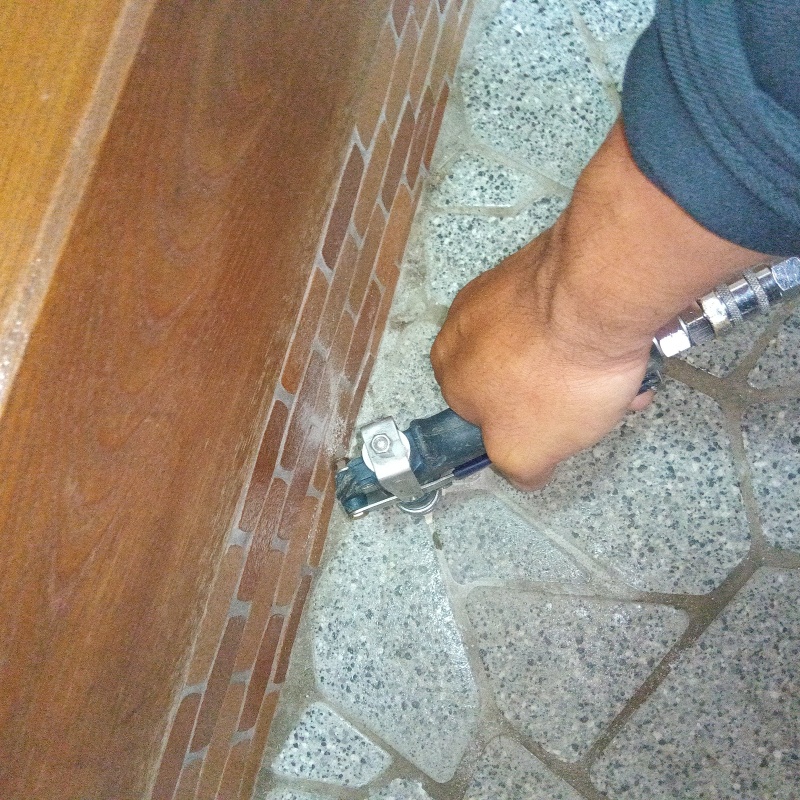 玄関の床にシロアリ駆除剤を注入する様子