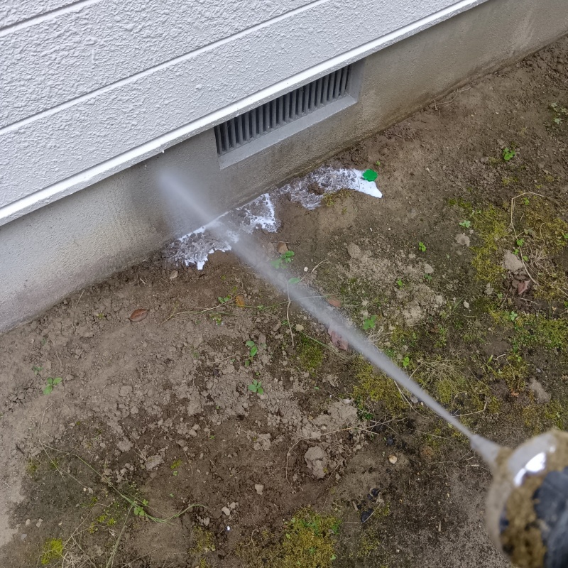 基礎まわりにシロアリ駆除剤を散布する様子