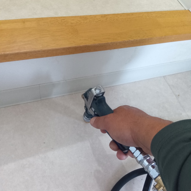 玄関の床にシロアリ駆除剤を注入する様子