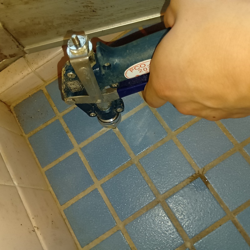 浴室の床にシロアリ駆除剤を注入する様子