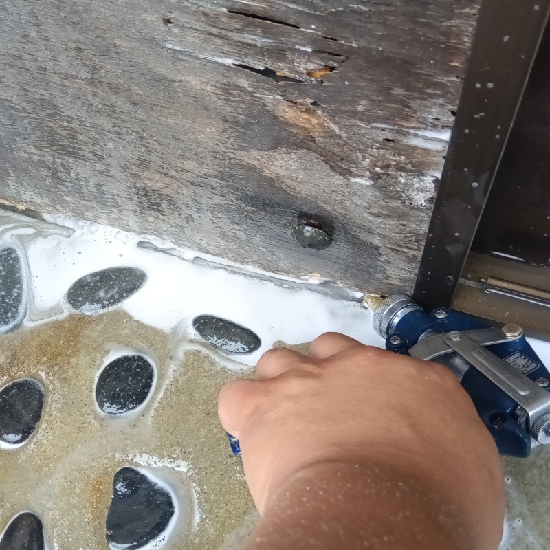 玄関の床にシロアリ駆除剤を注入する様子