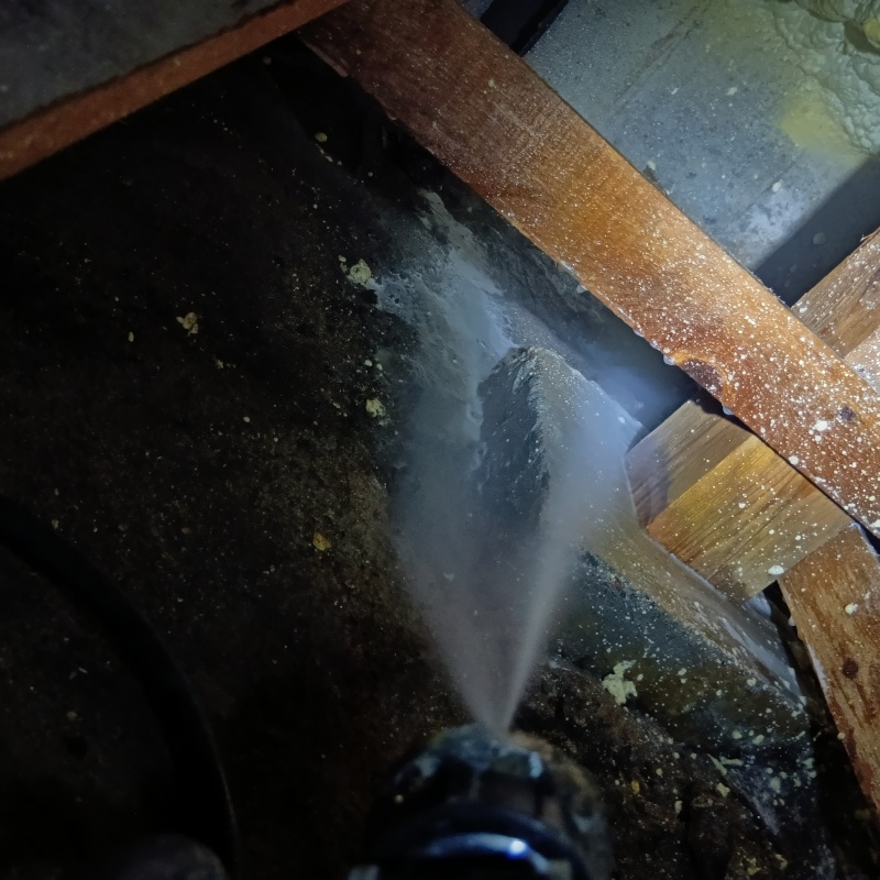 床下の土壌にシロアリ駆除剤を散布する様子