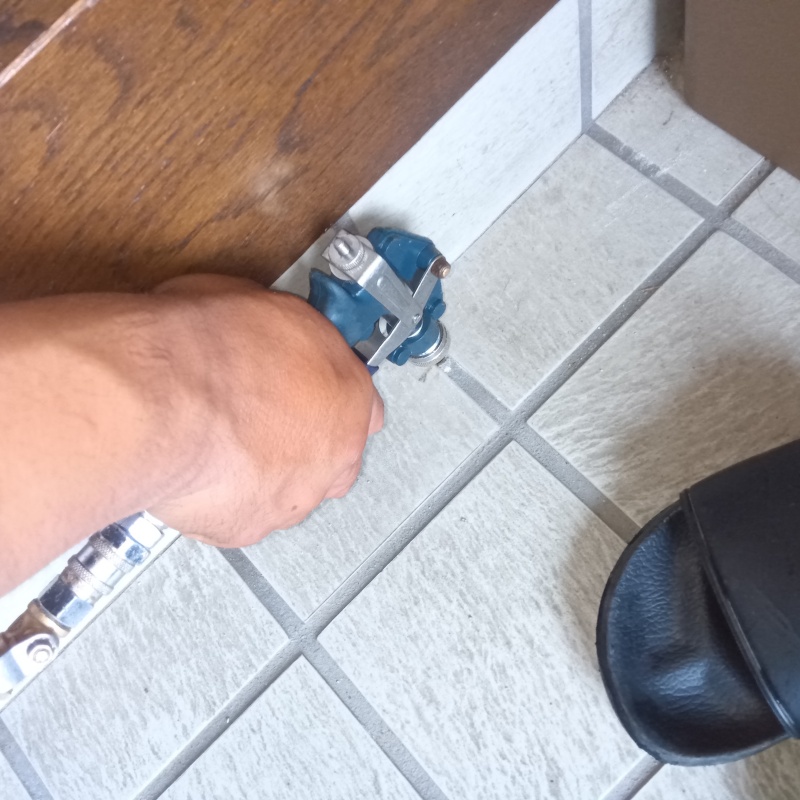 玄関の床にシロアリ駆除剤を注入する様子