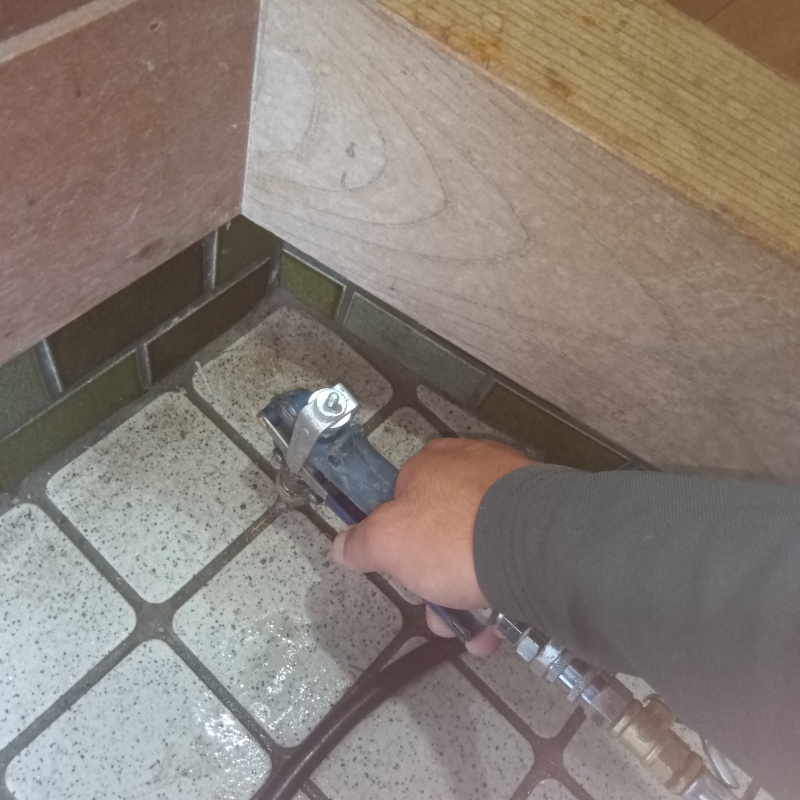 玄関の床にシロアリ駆除剤を注入する様子