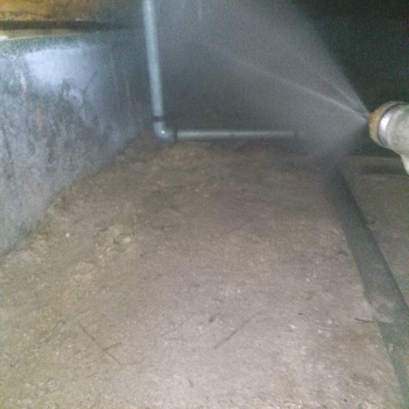 床下の土壌にシロアリ駆除剤を散布する様子