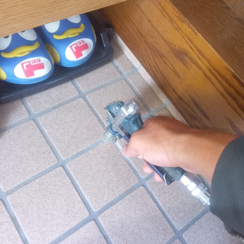 玄関の床にシロアリ駆除剤を注入する様子