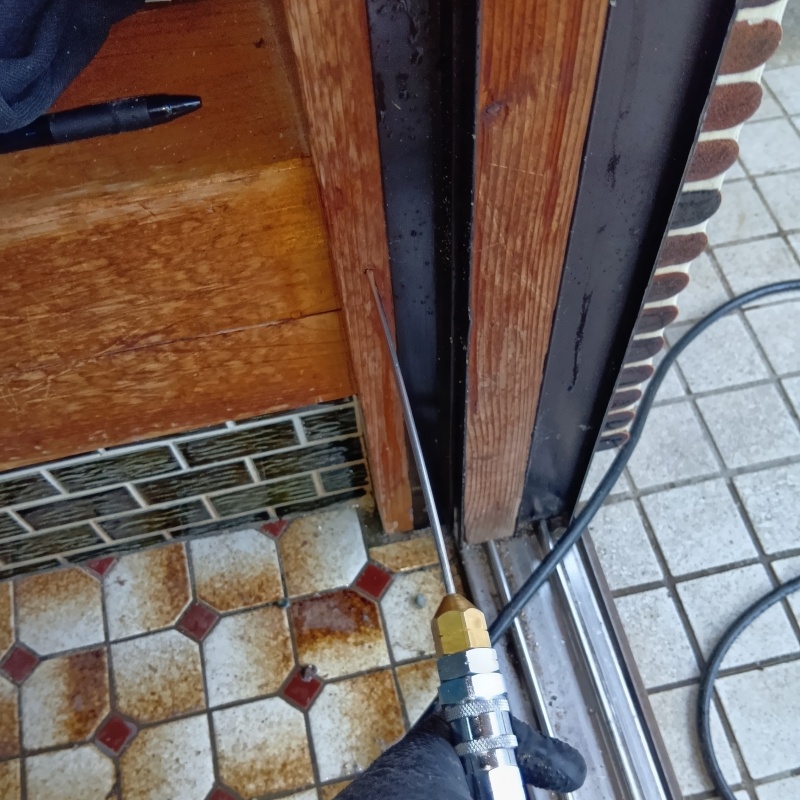 玄関の縦枠にシロアリ駆除剤を注入する様子