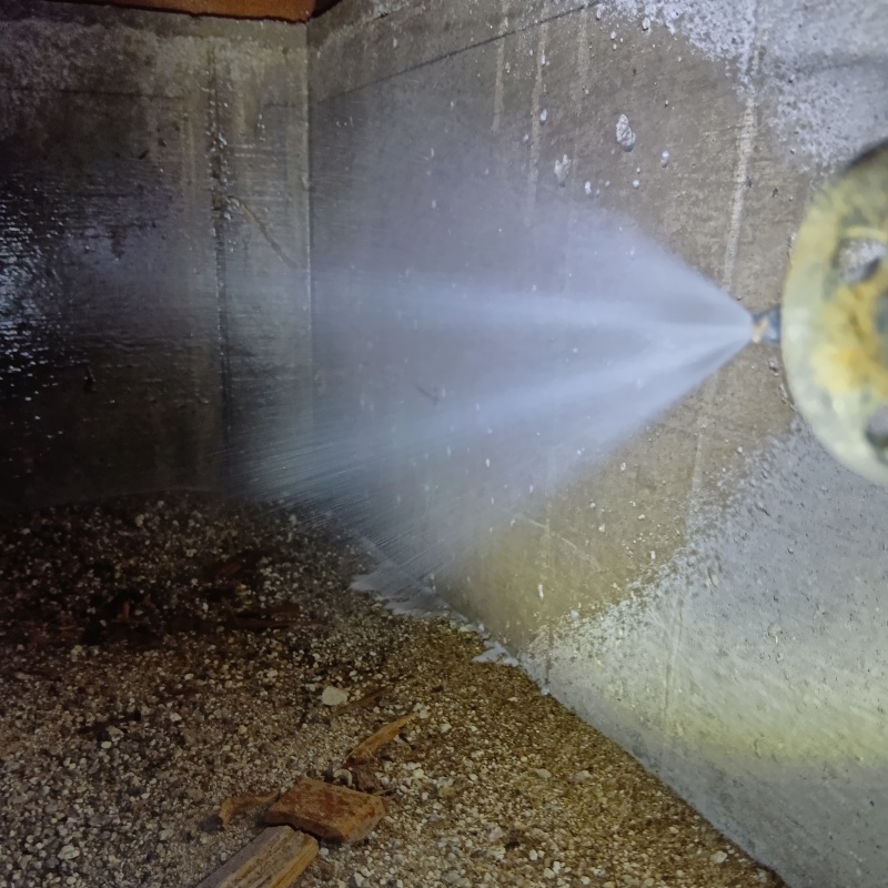 床下の基礎部分にシロアリ駆除剤を散布する様子